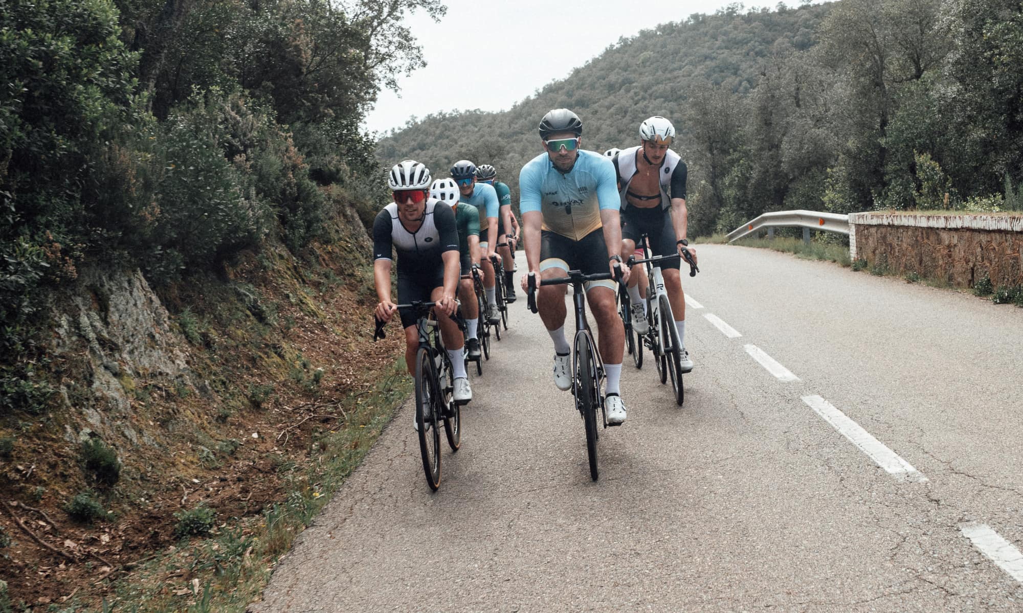 Een groep HYTX-fietsers rijdt samen een heuvelweg op aan de Costa Brava